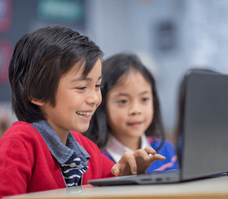 students sitting together at a table looking at one open laptop screen.